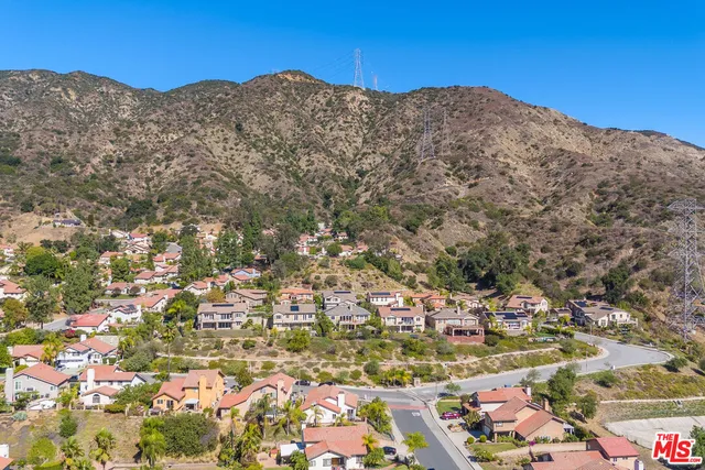 a view of a house with a small yard and large trees