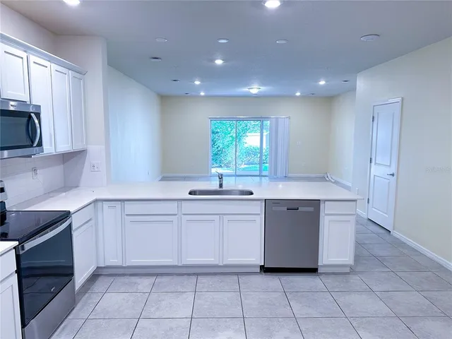 a large white kitchen with a sink window and cabinets