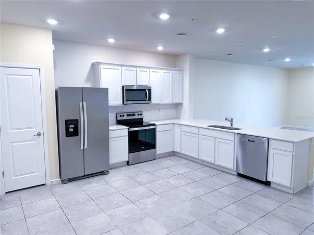 a large kitchen with a refrigerator sink and cabinets