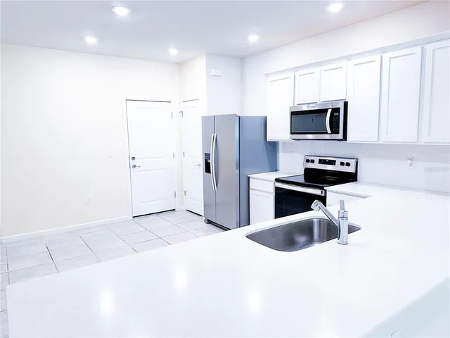 a kitchen with stainless steel appliances kitchen island a refrigerator sink and microwave