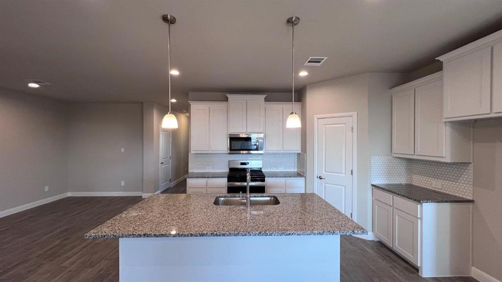 138 Stanton Avenue Rhome, TX 76078 - Photo 17 of 19 a kitchen with kitchen island granite countertop a sink a counter top space and stainless steel appliances