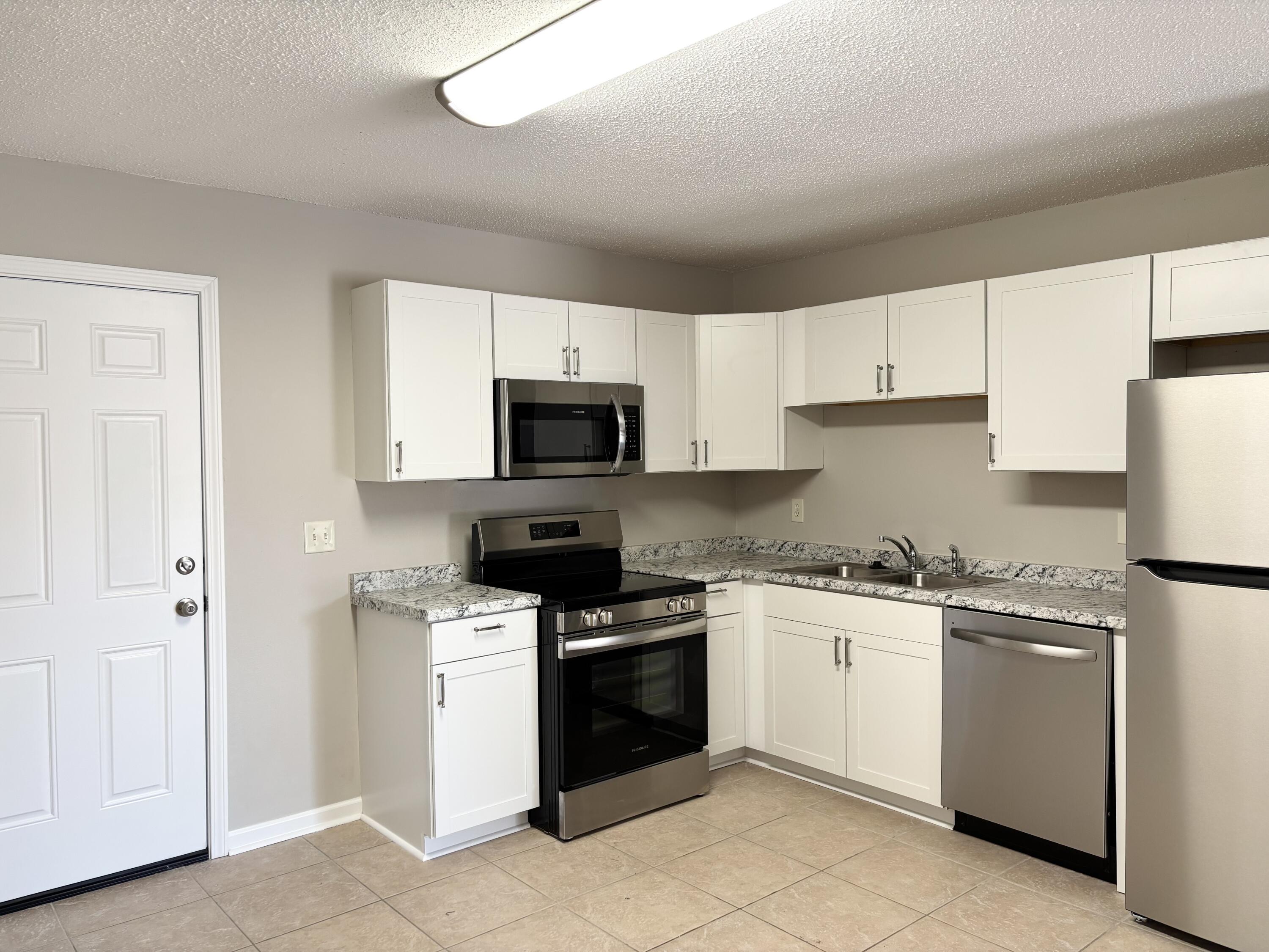 316 Lewis Street, Unit D Fort Walton Beach, FL 32547 - Photo 5 of 9 a kitchen with white cabinets and white appliances