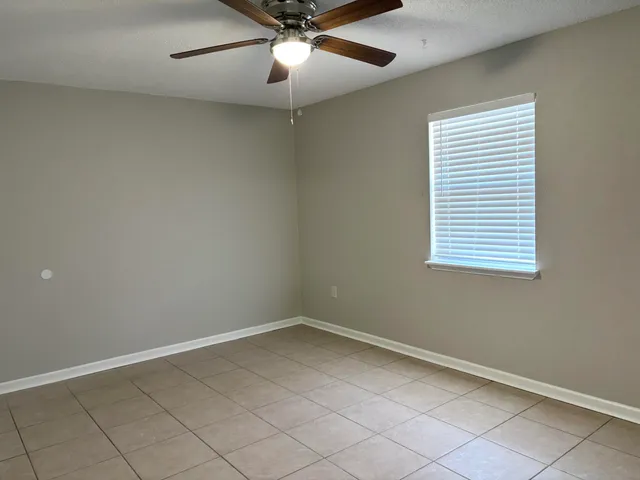 an empty room with a window and ceiling fan