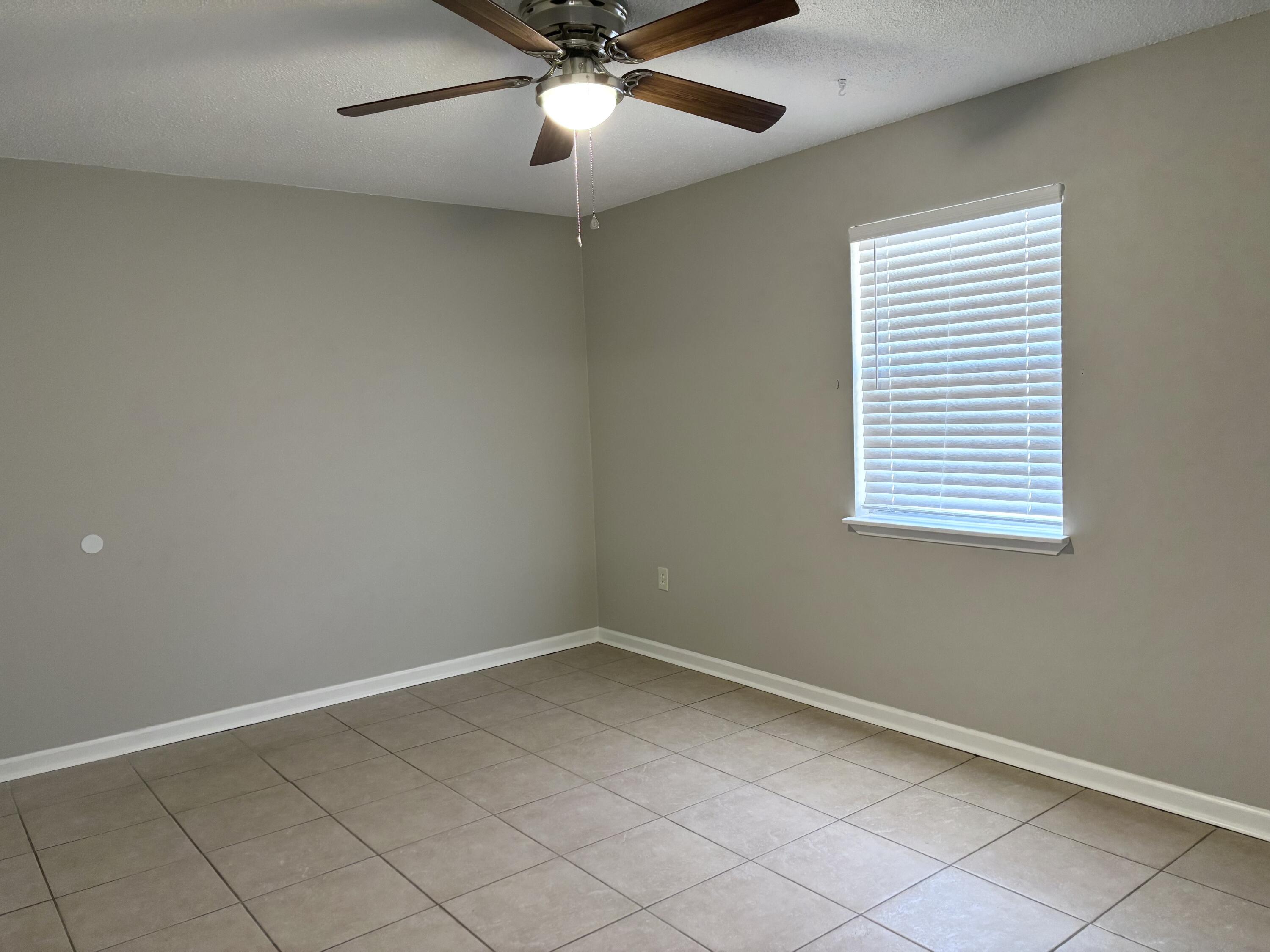 316 Lewis Street, Unit D Fort Walton Beach, FL 32547 - Photo 6 of 9 an empty room with a ceiling fan and window