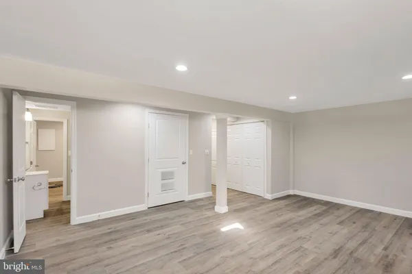 a view of an empty room with wooden floor and a bathroom