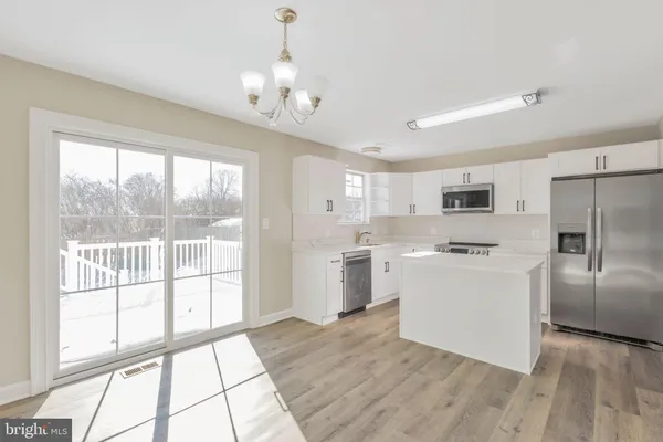 a kitchen with a refrigerator a stove top oven and a large window with wooden floor