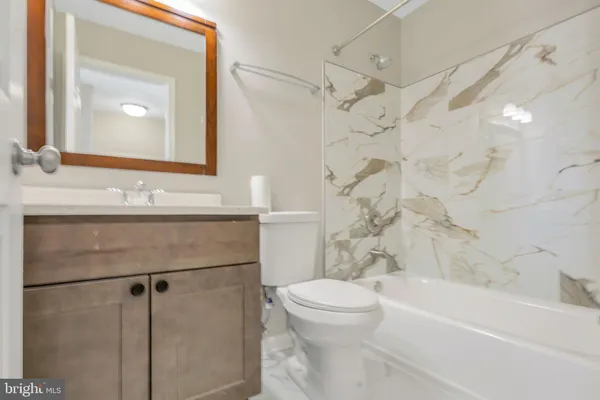 a bathroom with a sink a toilet a mirror a vanity and bathtub