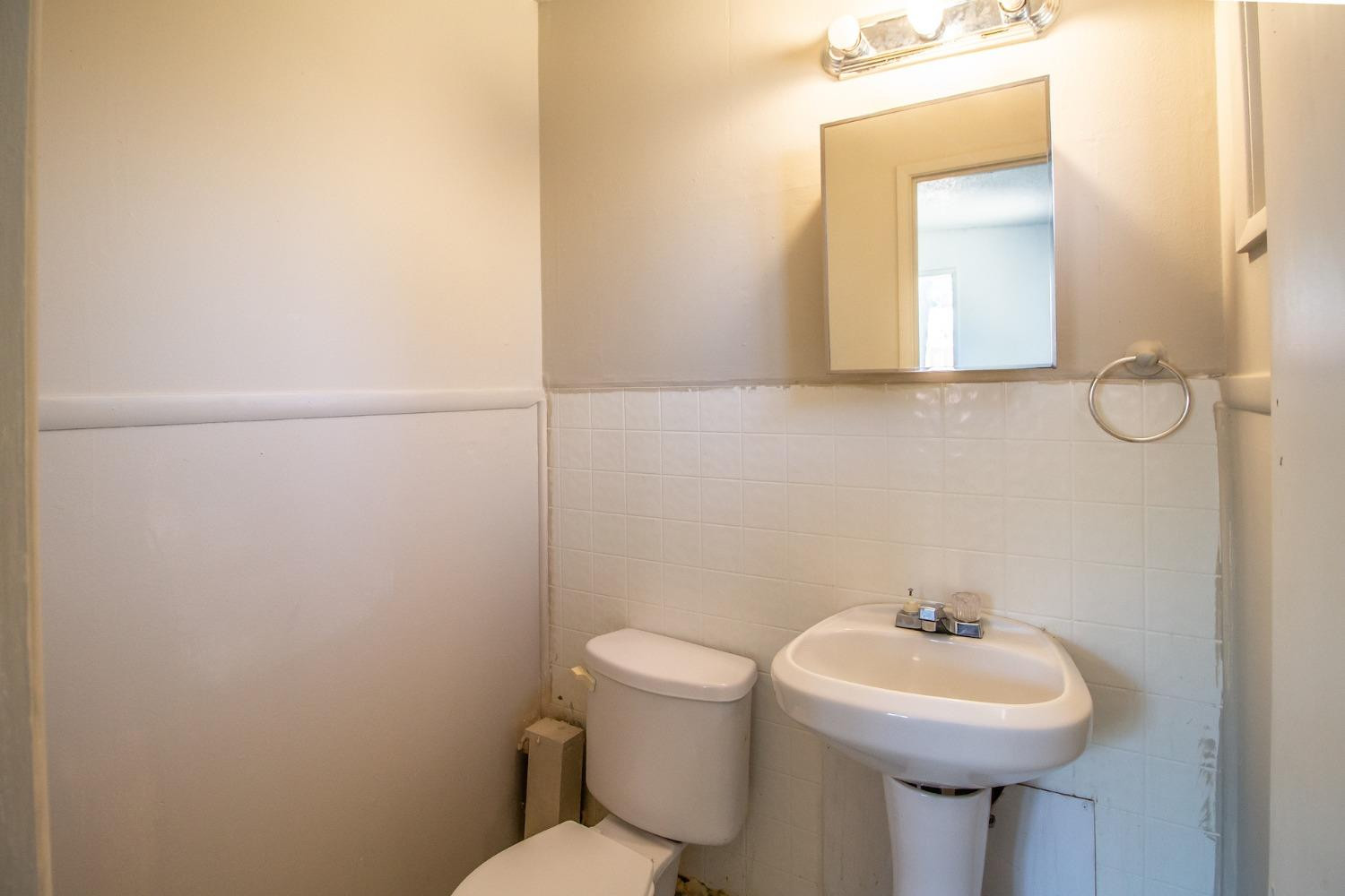 2714 62nd Street Lubbock, TX 79413 - Photo 22 of 28 a bathroom with a sink mirror and toilet