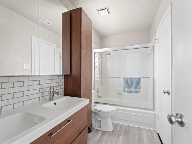 a bathroom with a granite countertop bathtub shower sink vanity and toilet