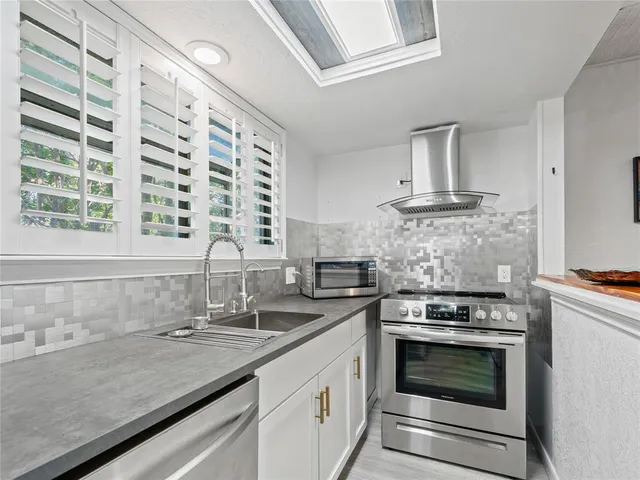 a kitchen with granite countertop a sink stainless steel appliances and cabinets
