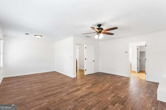 an empty room with windows and ceiling fan