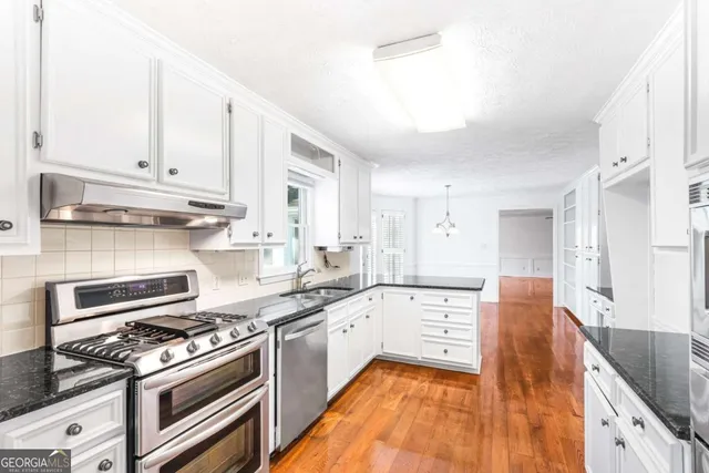 a large kitchen with stainless steel appliances granite countertop a stove and a sink