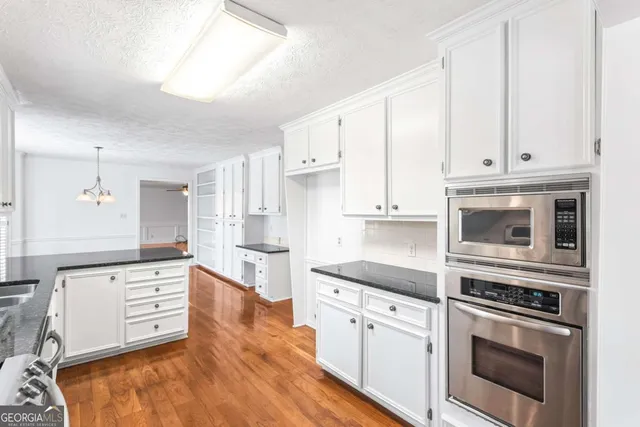 a kitchen with stainless steel appliances granite countertop a stove and white cabinets