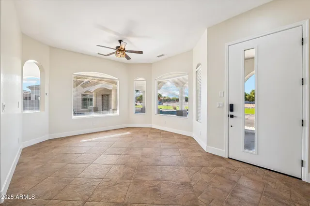 a view of an empty room with window and chandelier fan