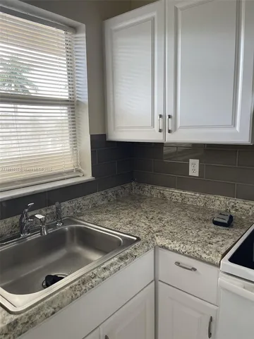 a kitchen with granite countertop white cabinets and a sink