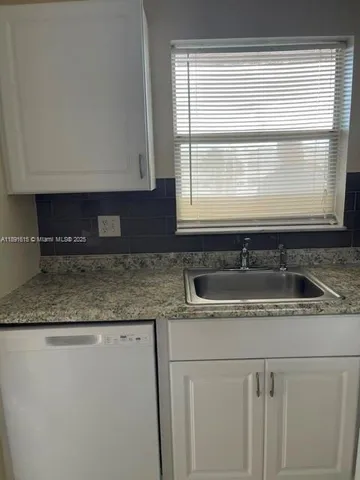 a kitchen with granite countertop cabinets sink and window