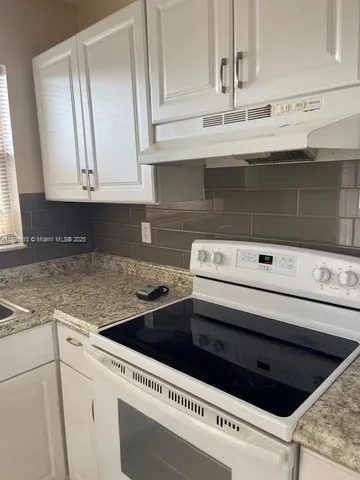 a kitchen with granite countertop white cabinets and black appliances