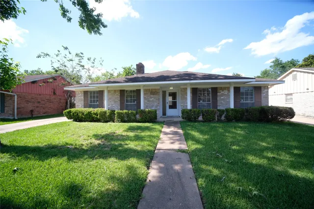 a front view of a house with a yard and potted plants