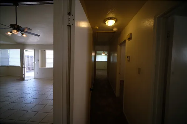 a view of a hallway with wooden floor and a bathroom with a sink