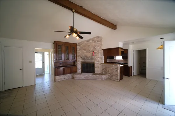 a view of a livingroom with a flat screen tv kitchen fireplace and windows