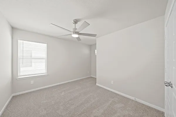 an empty room with a window and a fan