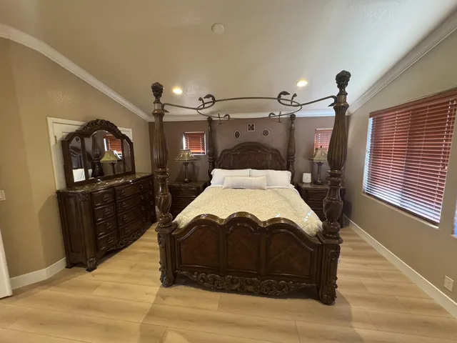a spacious bedroom with a bed window and dresser