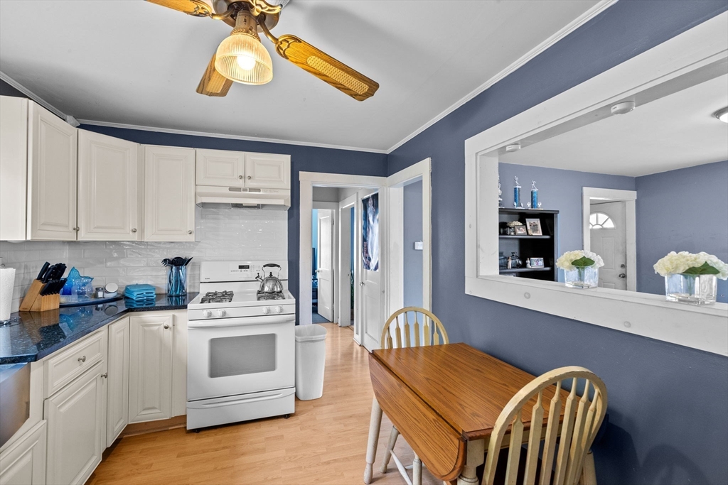 435 Newport Road Hull, MA 02045 - Photo 22 of 35 a kitchen with stainless steel appliances granite countertop a stove a sink dishwasher and white cabinets with wooden floor