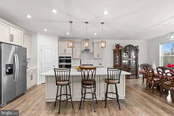 a open kitchen with stainless steel appliances granite countertop a stove a refrigerator a sink dishwasher and white cabinets with wooden floor