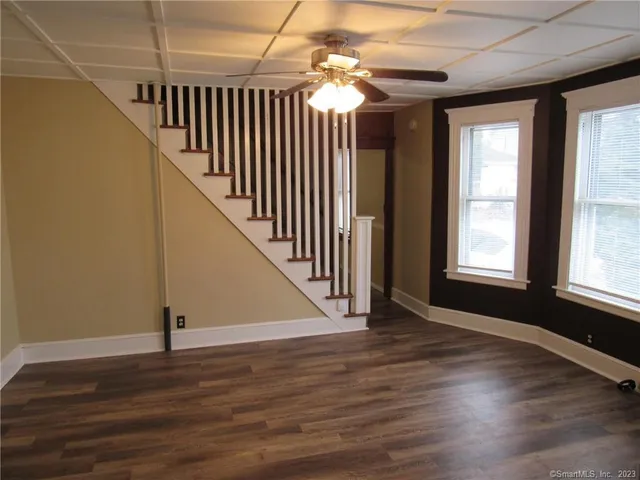 a view of empty room with wooden floor and fan