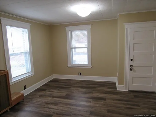 an empty room with wooden floor and windows