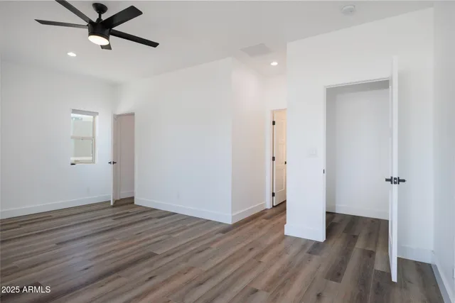 an empty room with wooden floor and a ceiling fan