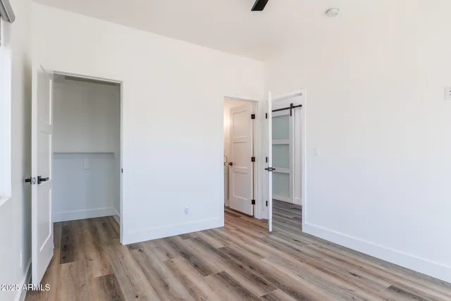 a view of an empty room with wooden floor and a ceiling fan