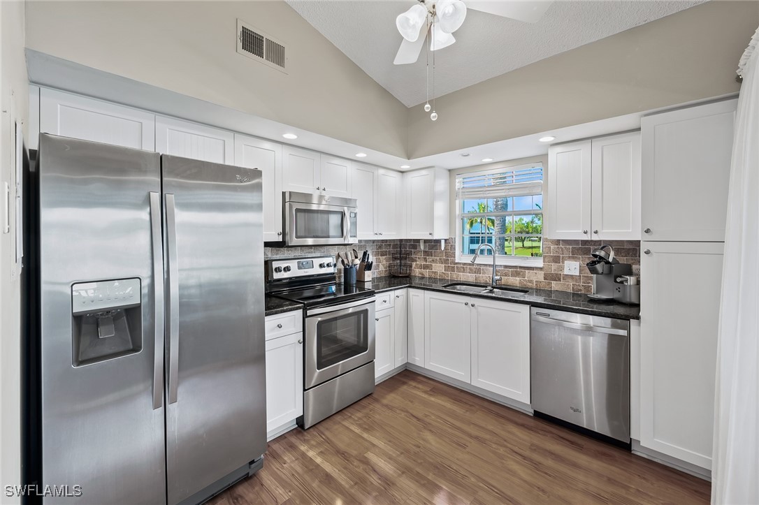 14979 Rivers Edge Court, Unit 223 Fort Myers, FL 33908 - Photo 7 of 18 a kitchen with stainless steel appliances granite countertop a refrigerator a stove a sink and white cabinets
