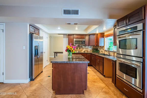 a kitchen with stainless steel appliances granite countertop a stove refrigerator and cabinets