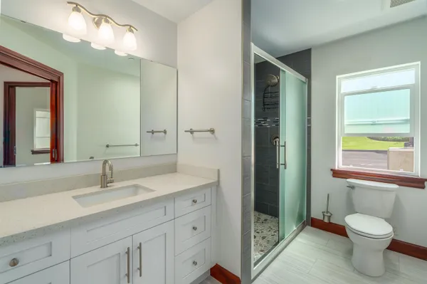 a bathroom with a toilet a sink a vanity a mirror and window