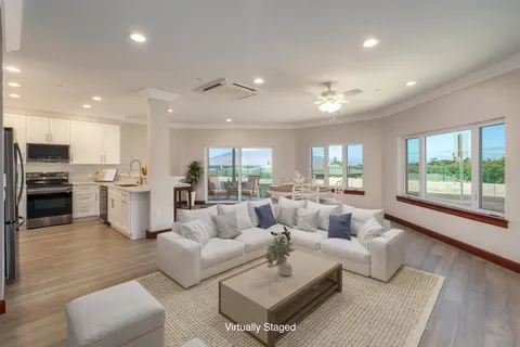 a living room with furniture and a large window with kitchen view