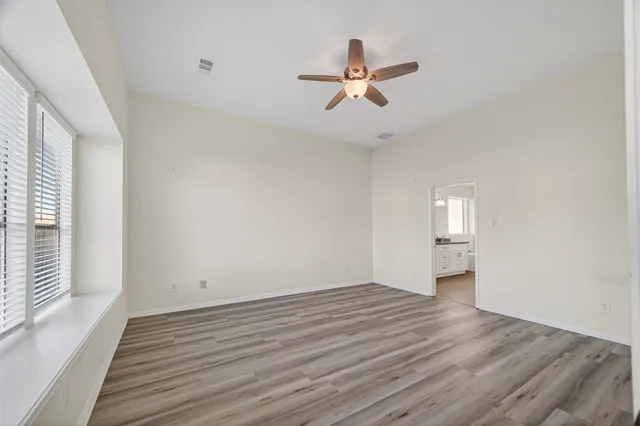 a view of empty room with wooden floor and fan