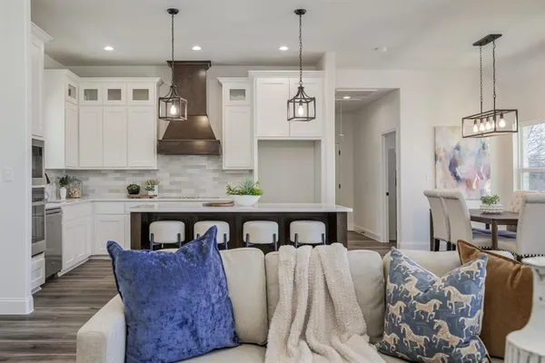 a living room with furniture a sink a kitchen island and a refrigerator