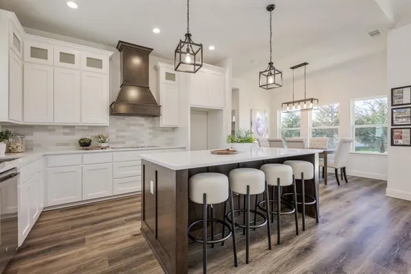 a kitchen with granite countertop a table chairs a sink dishwasher refrigerator and wooden floor