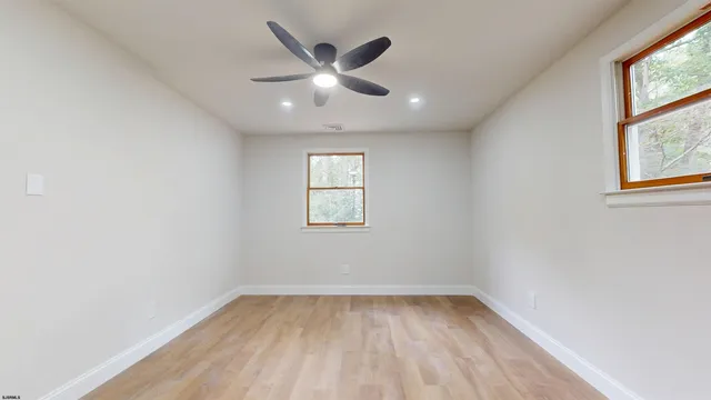 an empty room with a window and ceiling fan