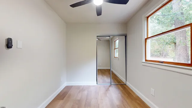 a view of empty room with wooden floor and fan