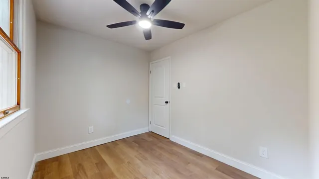 an empty room with a window and a fan