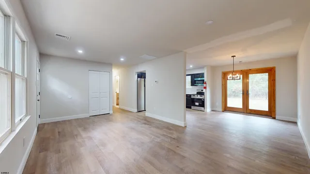 a view of an empty room with a window and wooden floor