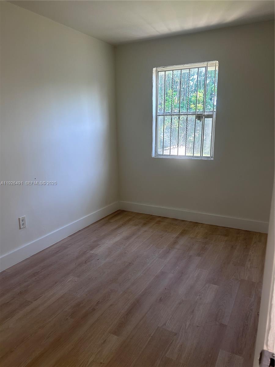 1820 Northwest 73rd Street, Unit 1820 Miami, FL 33147 - Photo 3 of 7 an empty room with wooden floor and windows