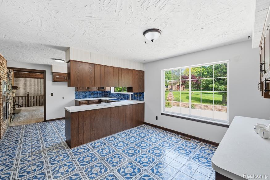 7020 Rattalee Lake Road Clarkston, MI 48348 - Photo 18 of 47 Kitchen featuring patterned blue and white floor tiles, wood-finish cabinetry, white countertops, and a full-size window