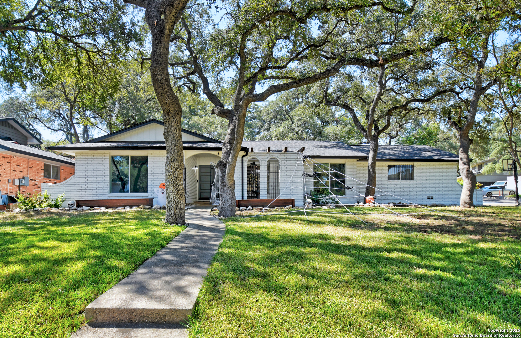 a front view of a house with a garden and trees