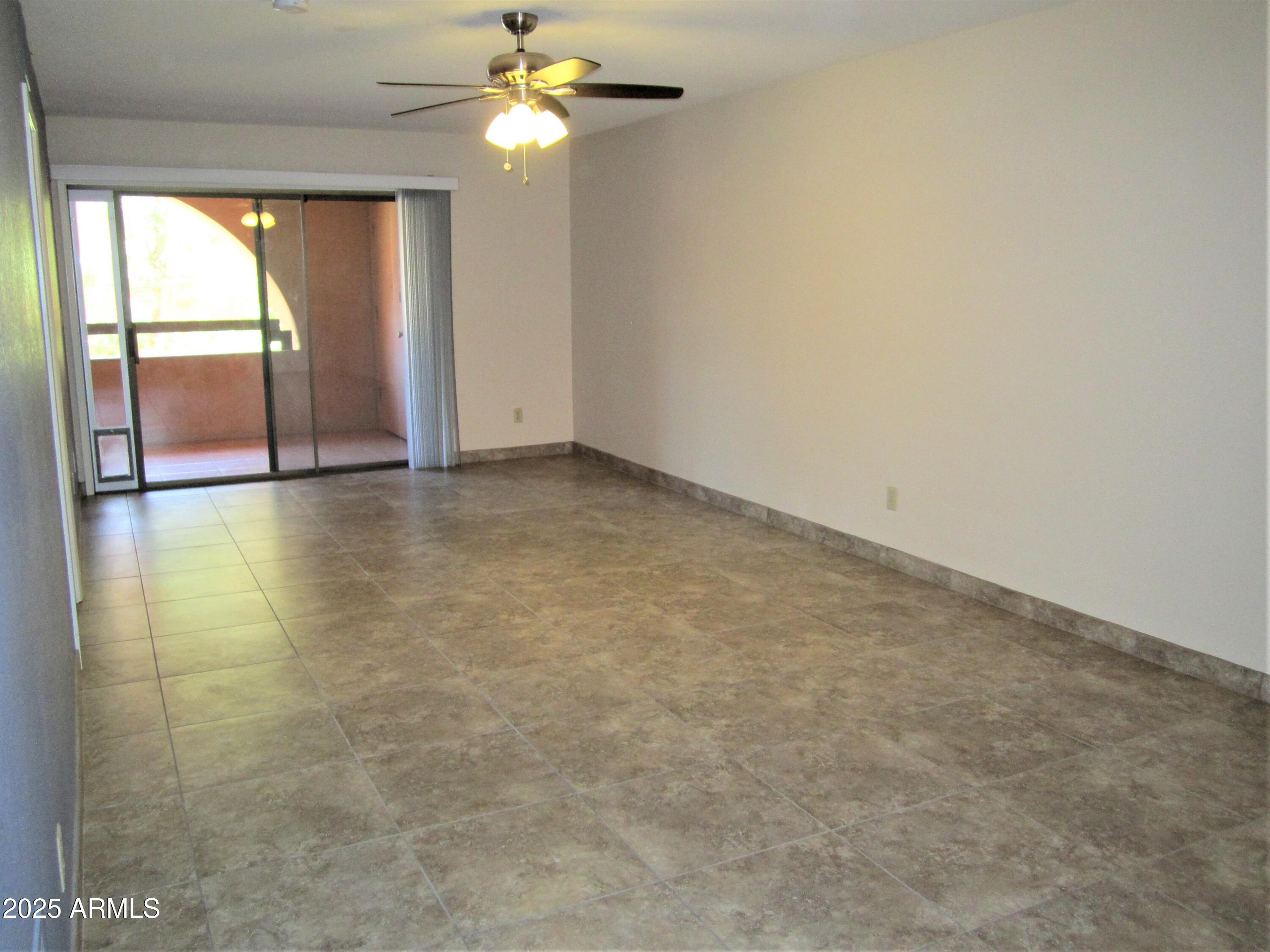 4303 East Cactus Road, Unit 310 Phoenix, AZ 85032 - Photo 3 of 27 an empty room with a chandelier fan and windows