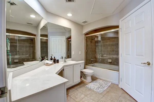 a bathroom with a bathtub shower sink mirror and toilet