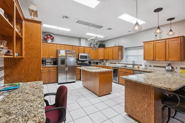 a kitchen with kitchen island granite countertop a sink stove and refrigerator