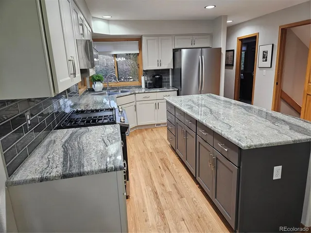 a kitchen with stainless steel appliances granite countertop a sink stove and refrigerator
